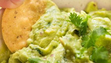 Close up of corn chip being dipped into Guacamole