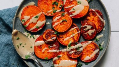 Plate of sliced sweet potatoes drizzled with tahini and parsley
