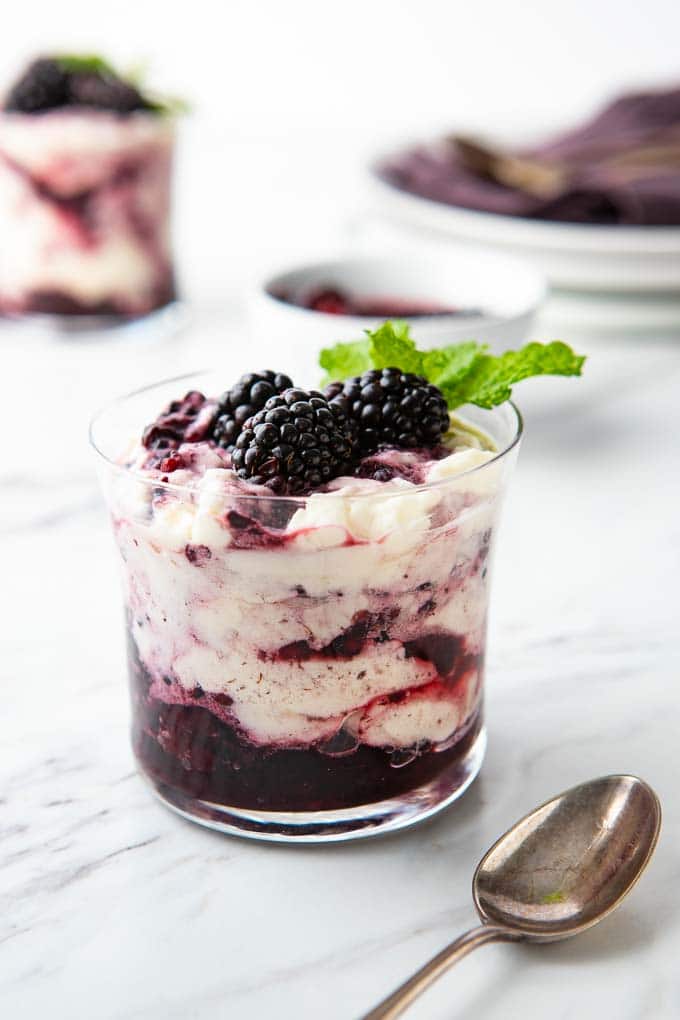 Glass of Blackberry Fool, garnished with blackberries and mint, with a spoon