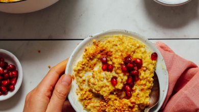Holding a bowl of Cozy Turmeric Porridge topped with bee pollen and pomegranate seeds